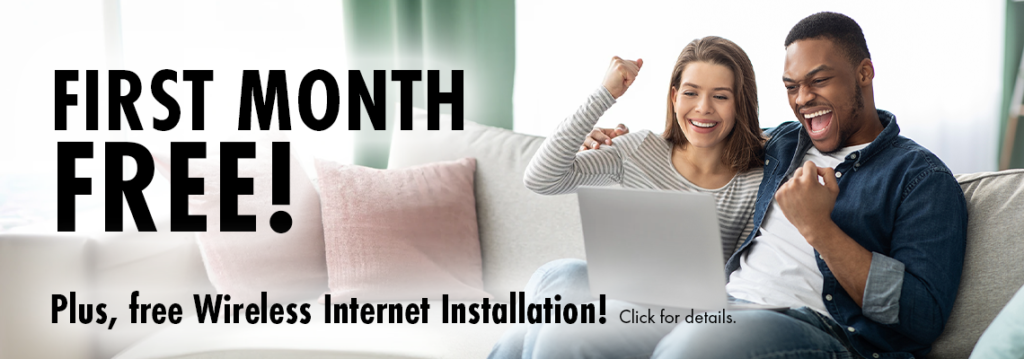 A woman and man sitting on a couch with a laptop, pumping their fists in the air. With the text, "First Month Free! Plus, free Wireless Internet Installation! Click for details."
